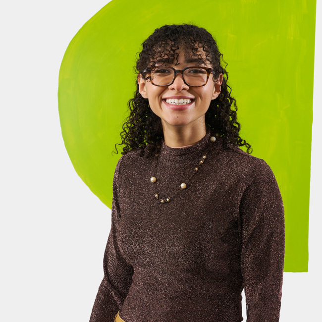 Photograph of a member of the Page 73 Playwriting workshop against a backdrop painted by Studio Usher